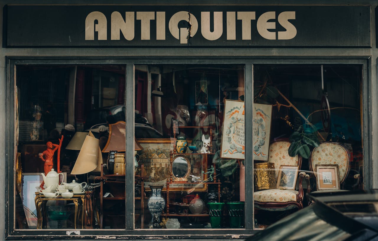 Explore a quaint Parisian antique shop with an elegant window display showcasing vintage treasures.